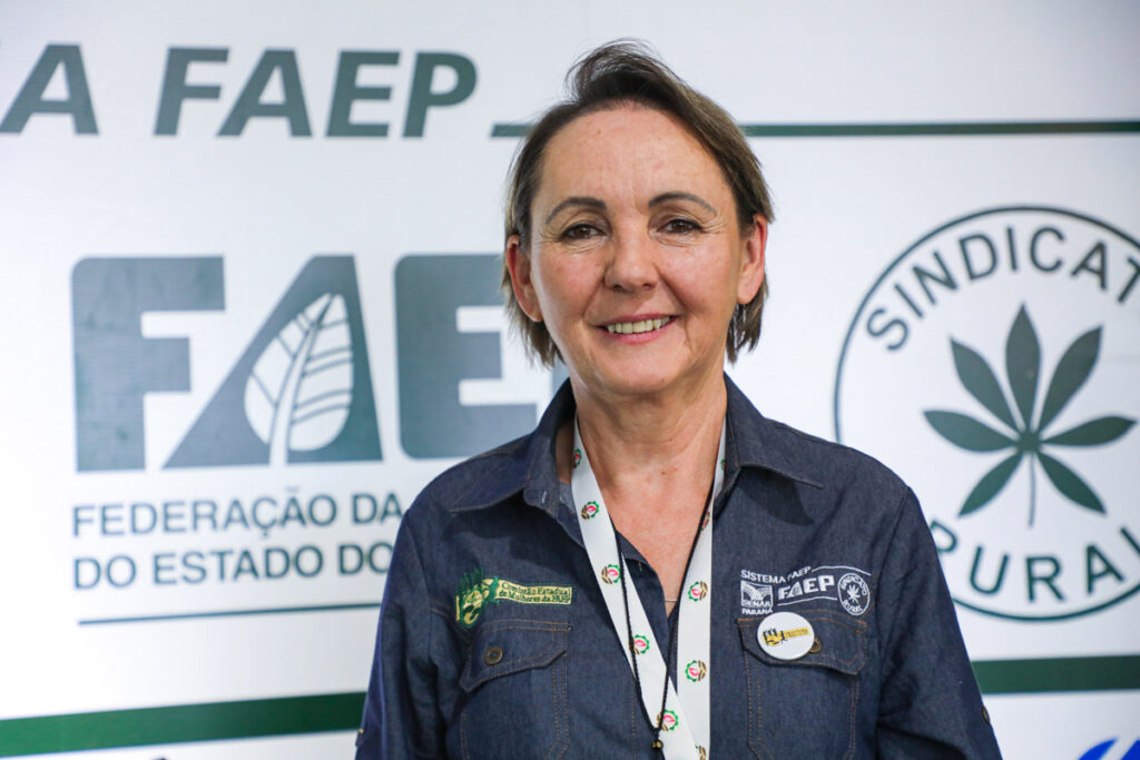 A produtora rural Edina Monczak Nova sorri, em frente a painel do Sistema FAEP/SENAR-PR