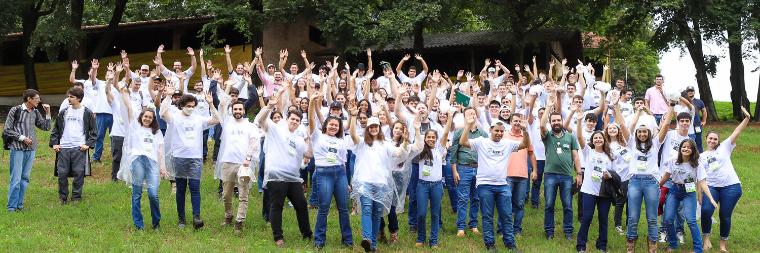 Participantes do Agrohackathon com os braços levantados em uma foto tirada ao ar livre