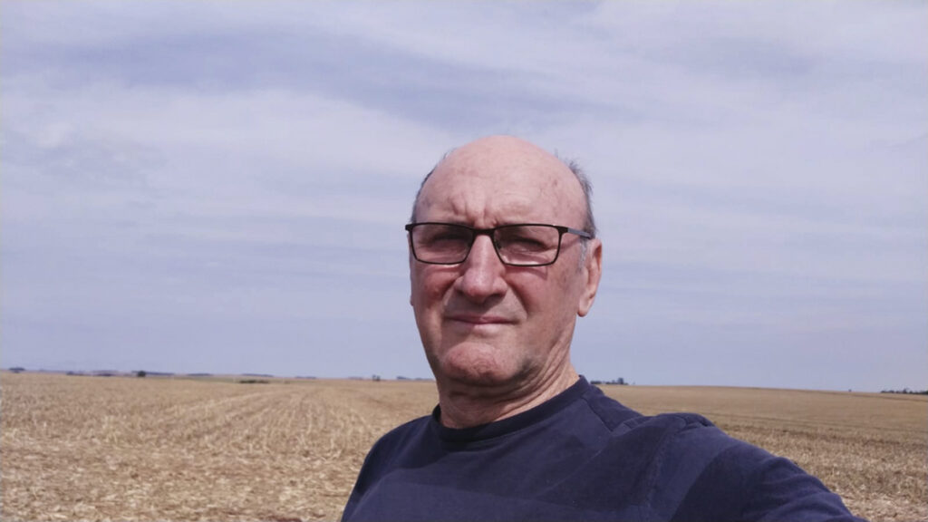 Produtor rural Milton Bernardtt em fotografia no estilo selfie, com lavoura seca no fundo