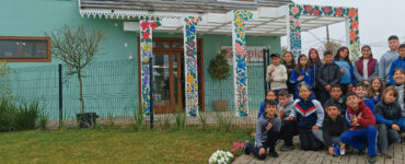 Alunos da professora Nilva Graboski posam para foto em frente a memorial da cultura polonesa