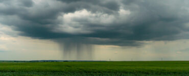 Paisagem rural com nuvens carregadas de chuva ao fundo; produtores rurais afetados pela chuva podem pedir renegociação de dívidas.