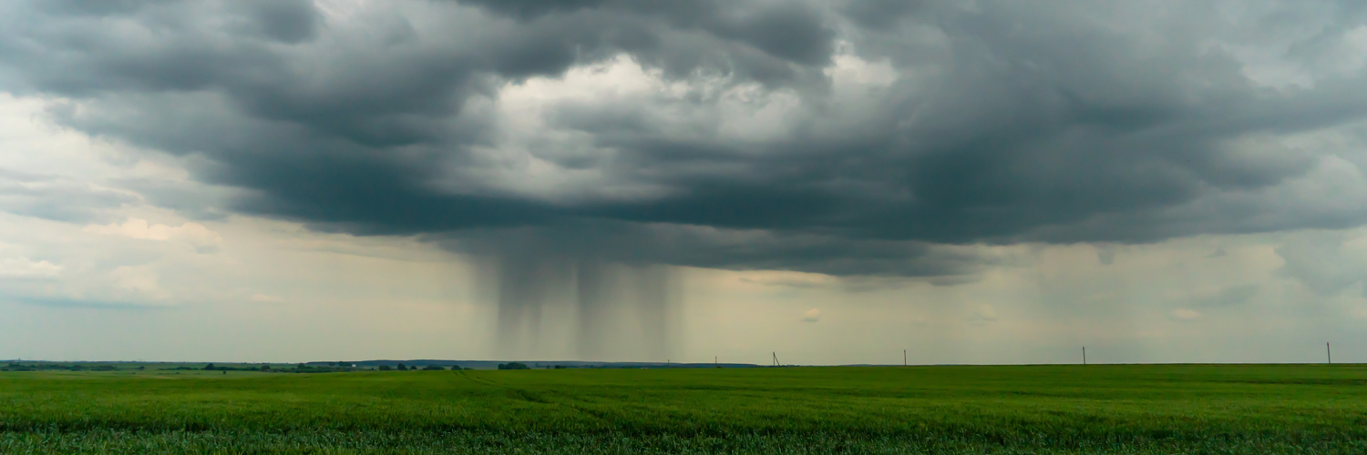 Paisagem rural com nuvens carregadas de chuva ao fundo; produtores rurais afetados pela chuva podem pedir renegociação de dívidas.