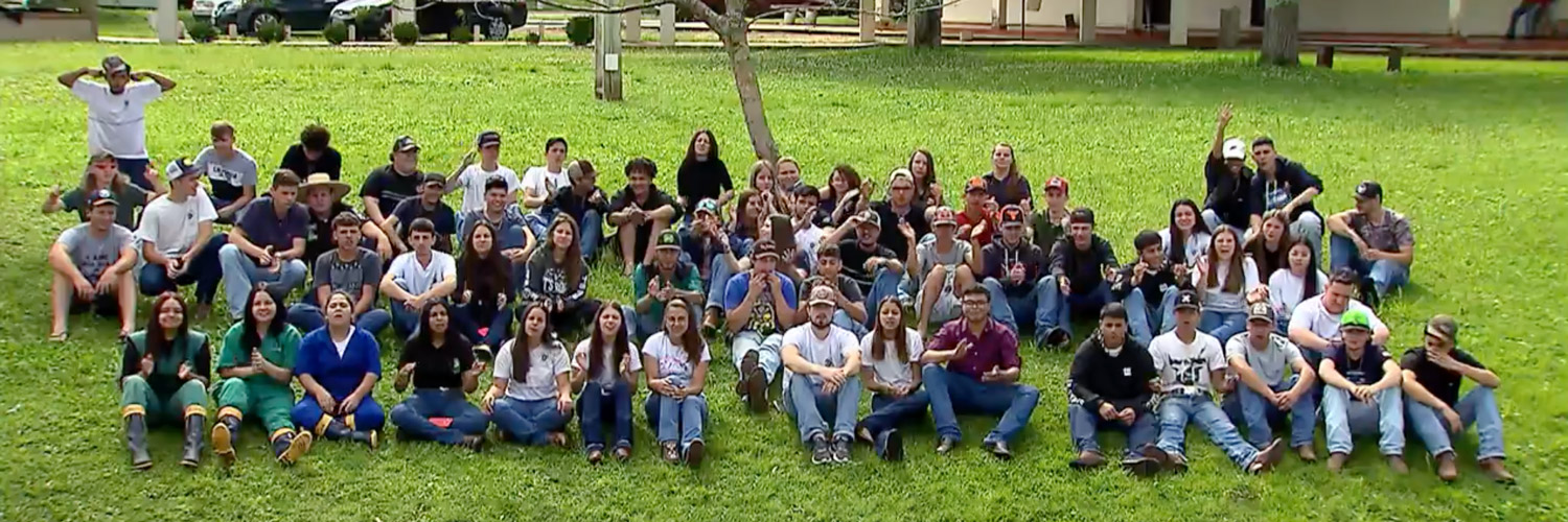 Frame do programa de TV Globo Rural no qual aparecem dezenas de estudantes de colégio agrícola de Castro sentados na grama lado a lado
